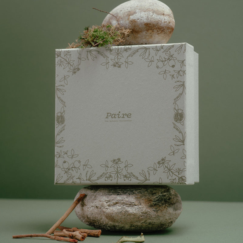 Sock gift box styled on a plinth against a deep green backdrop